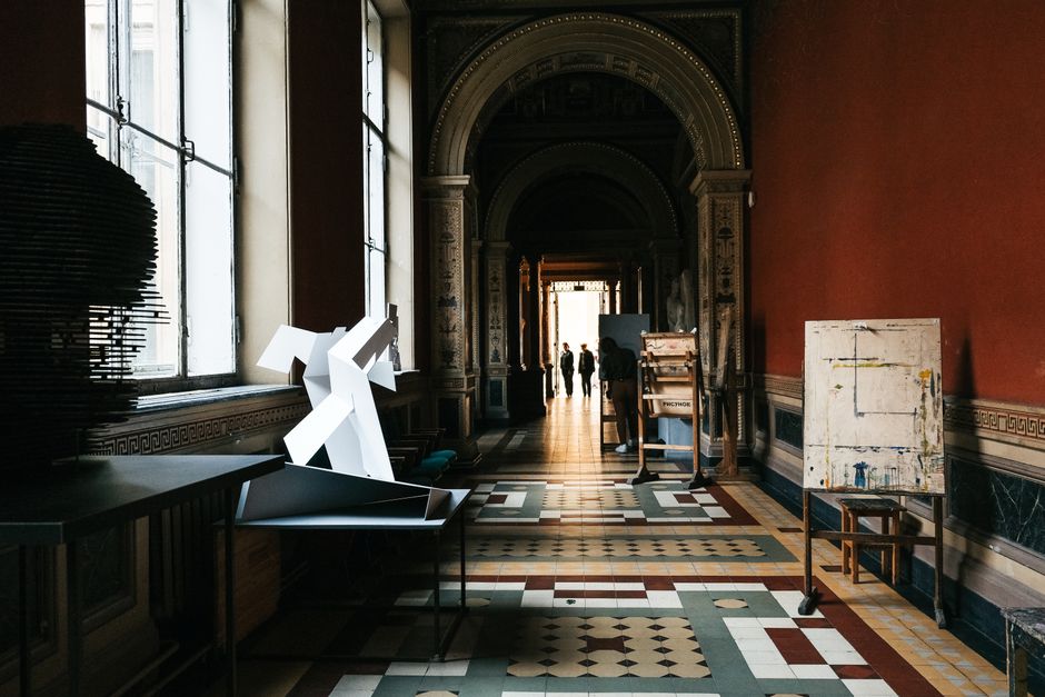 Dimly lit museum hallway with contemporary art installations and vibrant historic architecture.