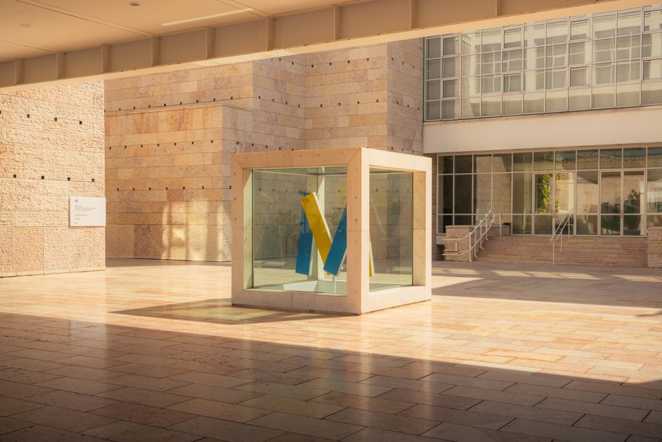 A modern art sculpture displayed in a glass case at a Lissabon museum courtyard.